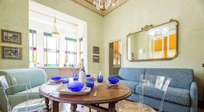 Un comedor con una mesa redonda, cristalería azul y un sofá azul.