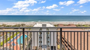 A view from a balcony overlooking a beach with a pool and a building with multiple floors and balconies. - Ocean Forest Plaza 912 (Myrtle Beach)