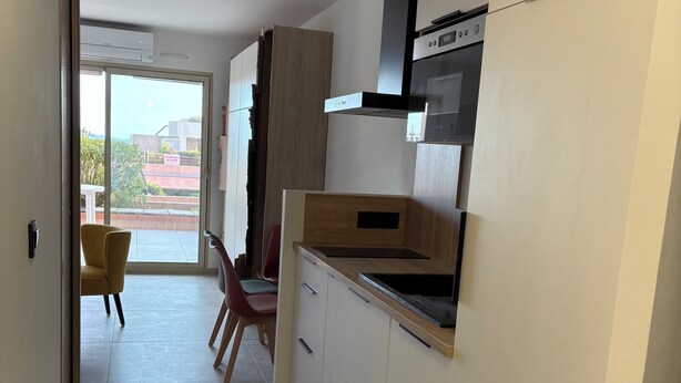 Uma cozinha moderna com armários brancos, bancada de madeira e exaustor preto.