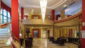 A spacious lobby with a grand staircase, a chandelier, and a second-floor balcony. - Hotel Mercure Krynica Zdroj Resort & Spa (Krynica-Zdroj)