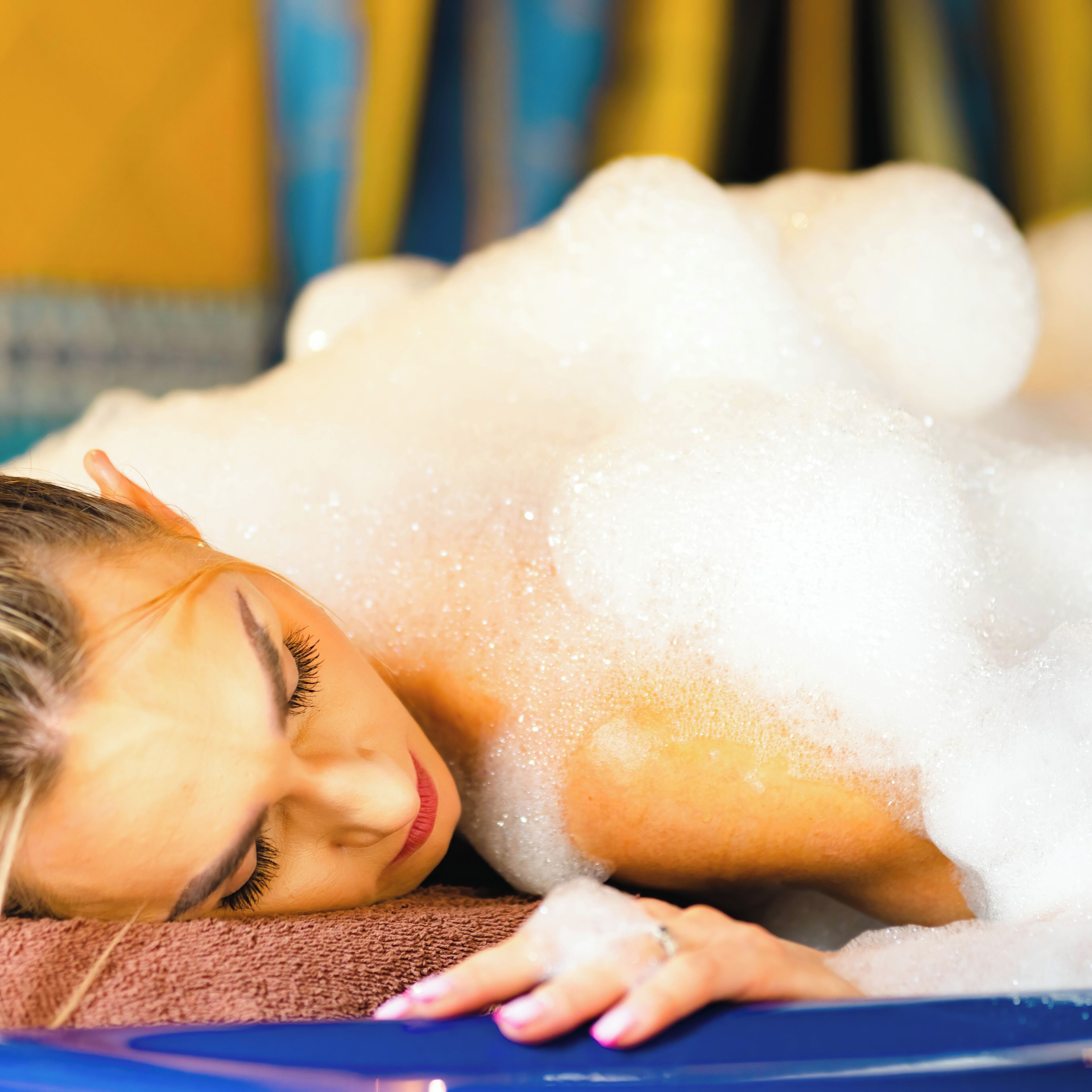 A person lying in a bathtub filled with bubbles.