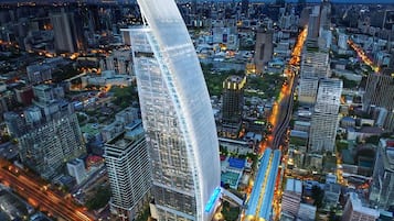 Un edificio moderno de gran altura con fachada curva, rodeado de un entorno urbano denso con calles y otros edificios a la vista.