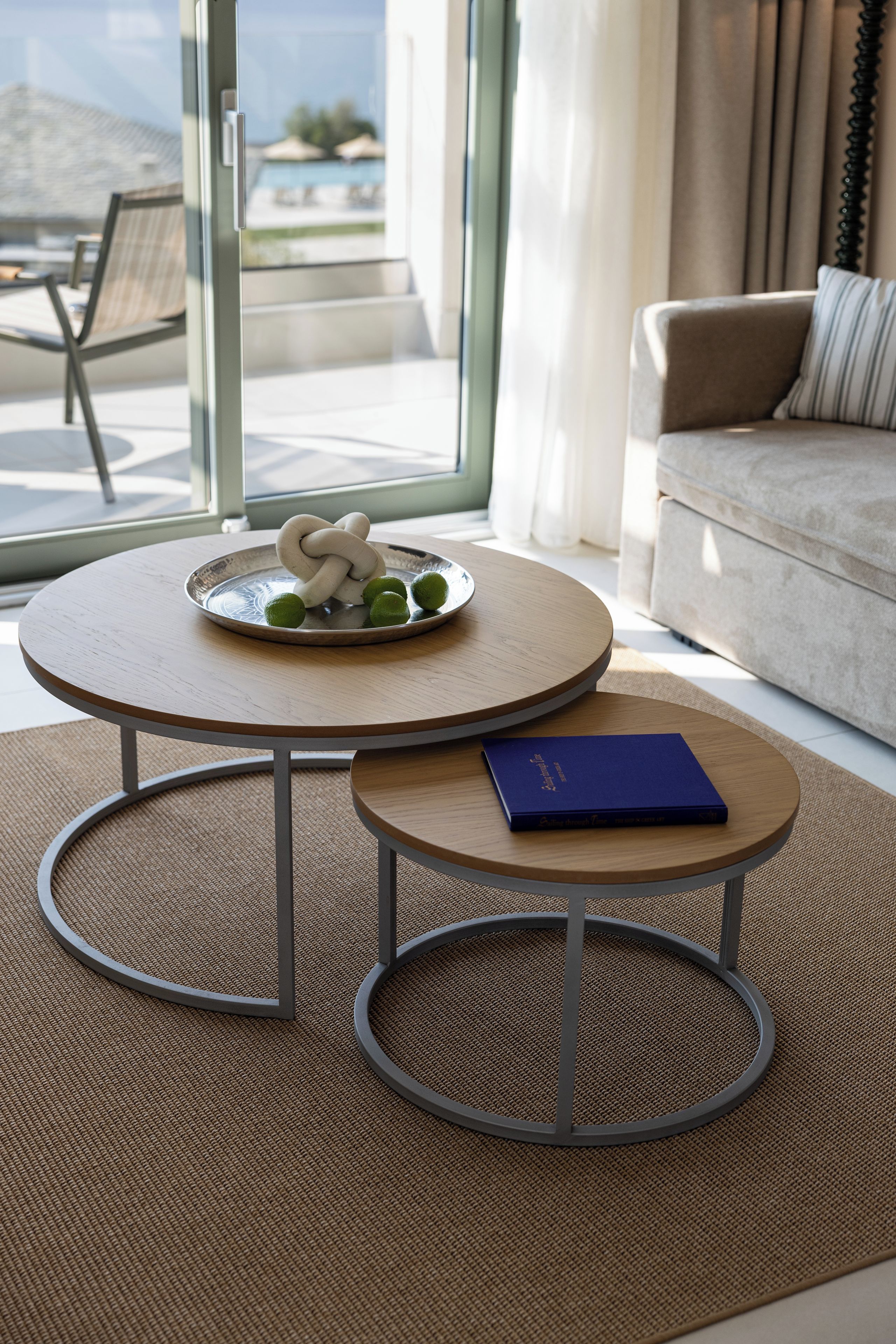 A modern living room with a round table, a sofa, and a view of the outdoors.