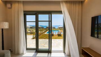 A room with a large sliding glass door leading to an outdoor pool area, a lamp, a TV, and a wooden bench.