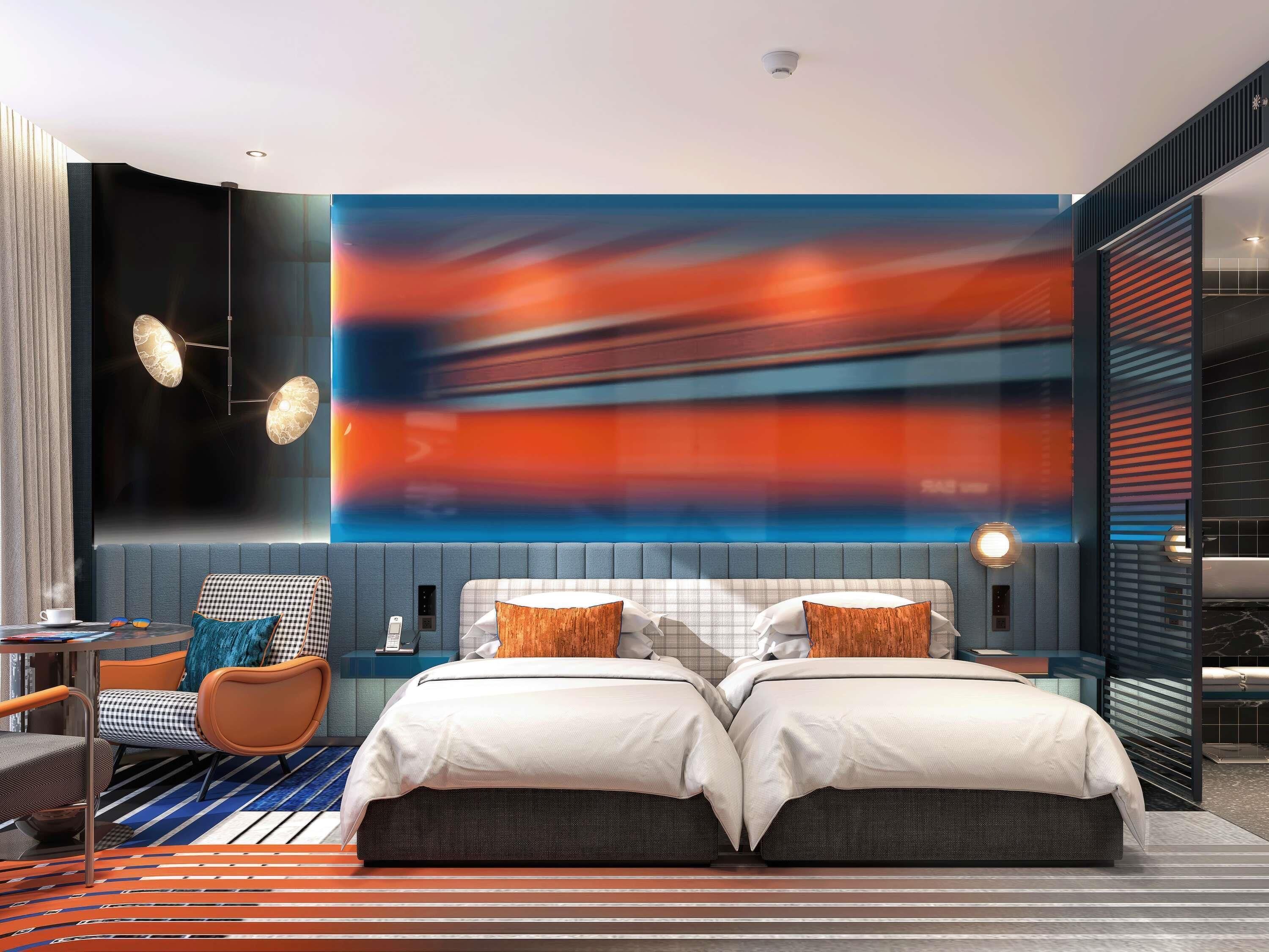 A modern hotel room with a large bed, a seating area with a table and chairs, and a large abstract painting on the wall.