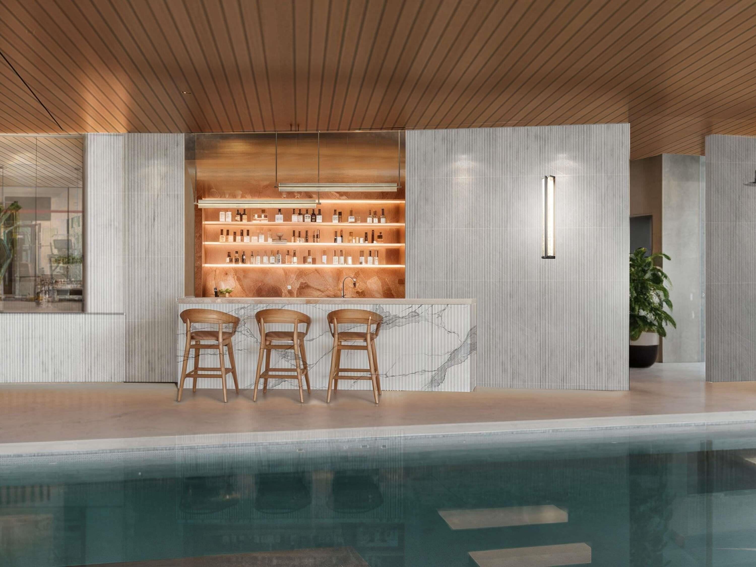 A bar area with a marble countertop, wooden chairs, and shelves of bottles.