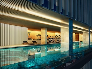 A modern indoor swimming pool with exercise equipment, a lounge area, and a view of the cityscape. - Mercure Bangkok Siam Ratchathewi (Bangkok)