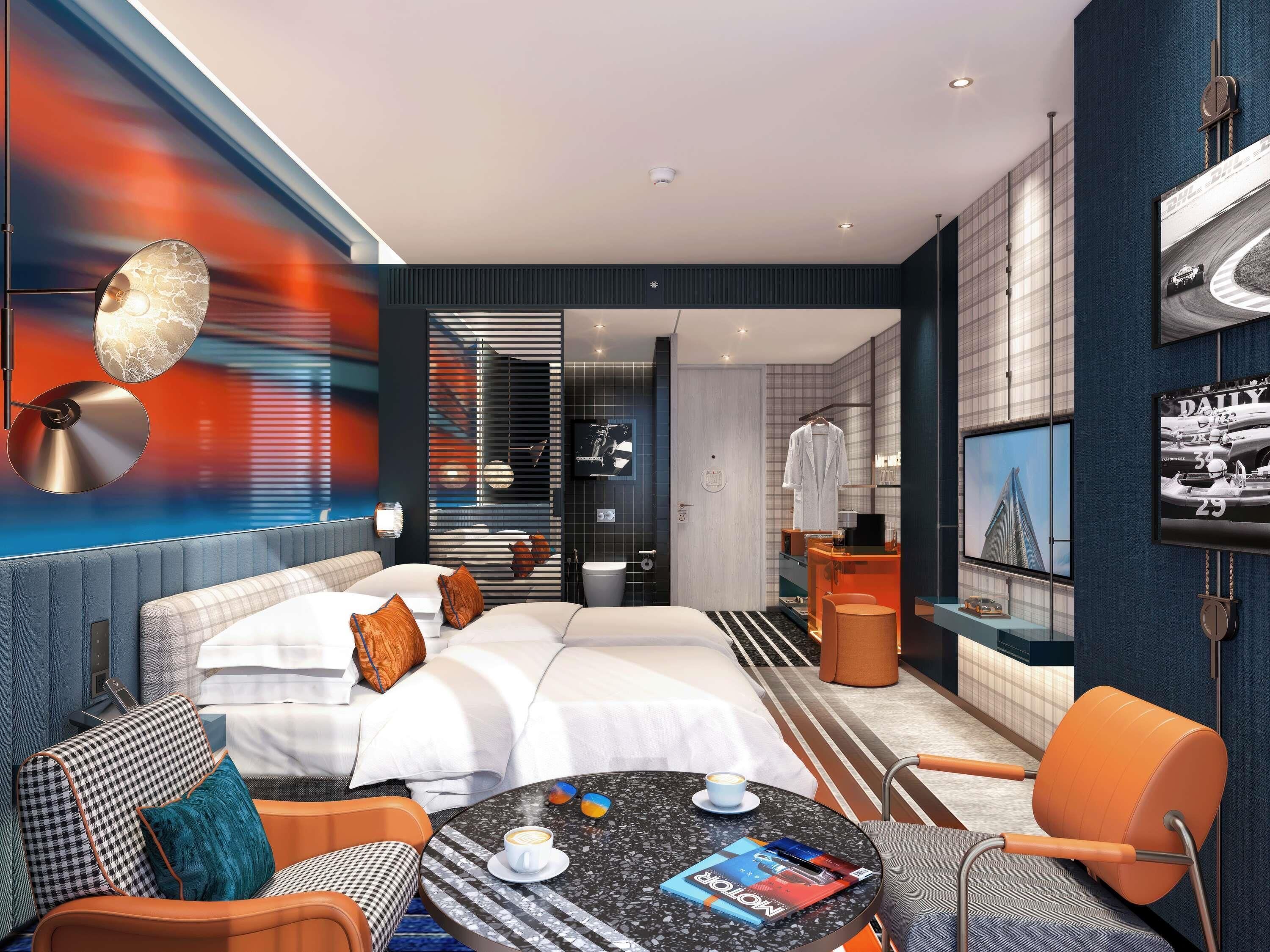 A modern hotel room with a large bed, a round table with a magazine, a coffee cup, and a TV on the wall.