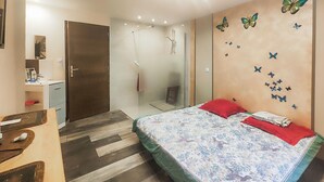 Quarto com cama, chuveiro, penteadeira de madeira e espelho.