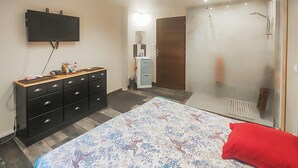 Quarto com cama, penteadeira, televisão, guarda-roupa e área de duche.