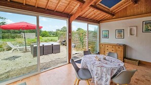 Ein Zimmer mit einer großen Schiebeglasdoor zum Außenbereich, einem Esstisch mit Stühlen und einer Holzschrank.