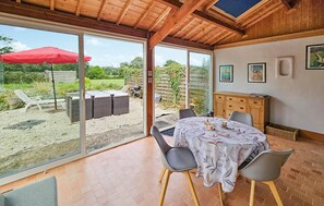 Ein Zimmer mit einer großen Schiebeglasdoor zum Außenbereich, einem Esstisch mit Stühlen und einer Holzschrank.