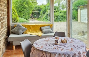 Ein gemütliches Zimmer mit einer Couch, einem Tisch und Blick auf einen Garten.