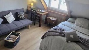 Et soveværelse med skrå vægge, en seng, en sofa, et skrivebord og en stol.