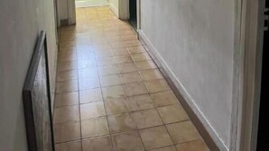 Een smalle gang met betegelde vloer en eenvoudige wanden.
