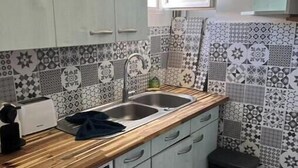 Een praktische keuken met een wasmachine, een spoelbak en een klein krukje.