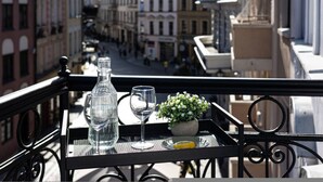 Un balcone con un tavolo apparecchiato per due, con una bottiglia, un bicchiere da vino e una piccola pianta in vaso.