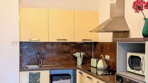 Een moderne keuken met een houten tafel, barstoelen, een inbouwoven en een magnetron.