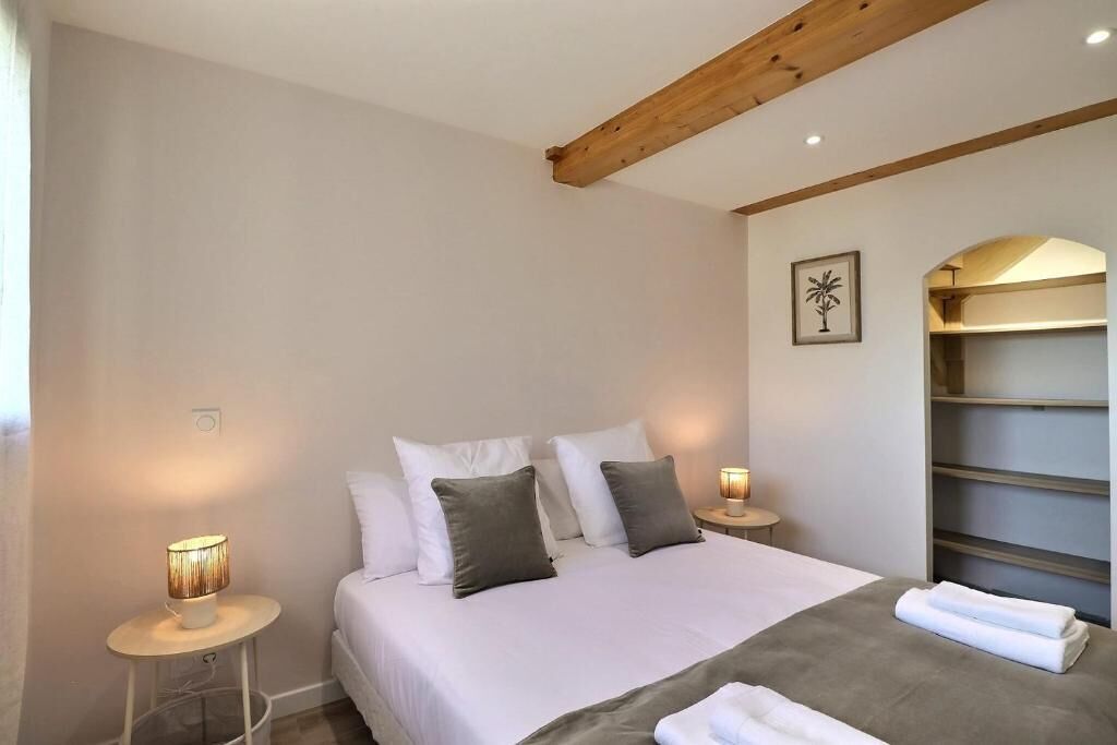 Una camera da letto con un letto, lampade sui comodini, una mensola a muro e un quadro incorniciato.