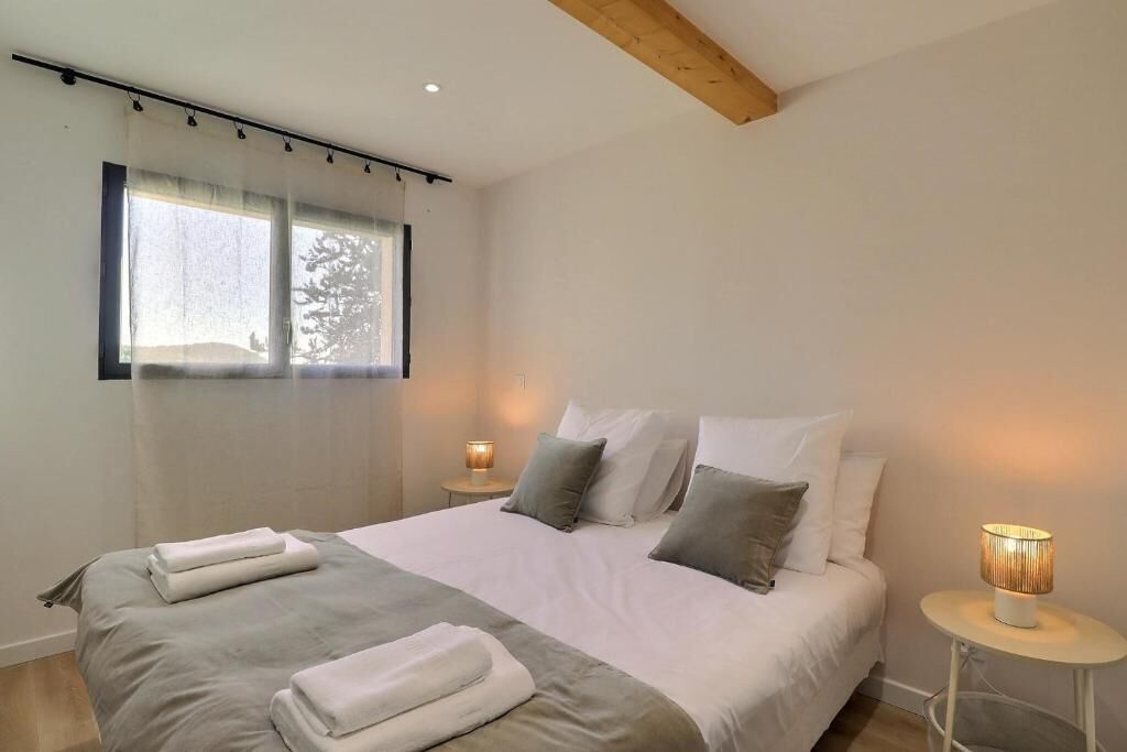 A bedroom with a bed, two bedside tables, and a window with curtains.