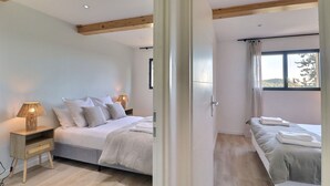 Una camera da letto con un letto, comodino, lampada e una finestra con tende.