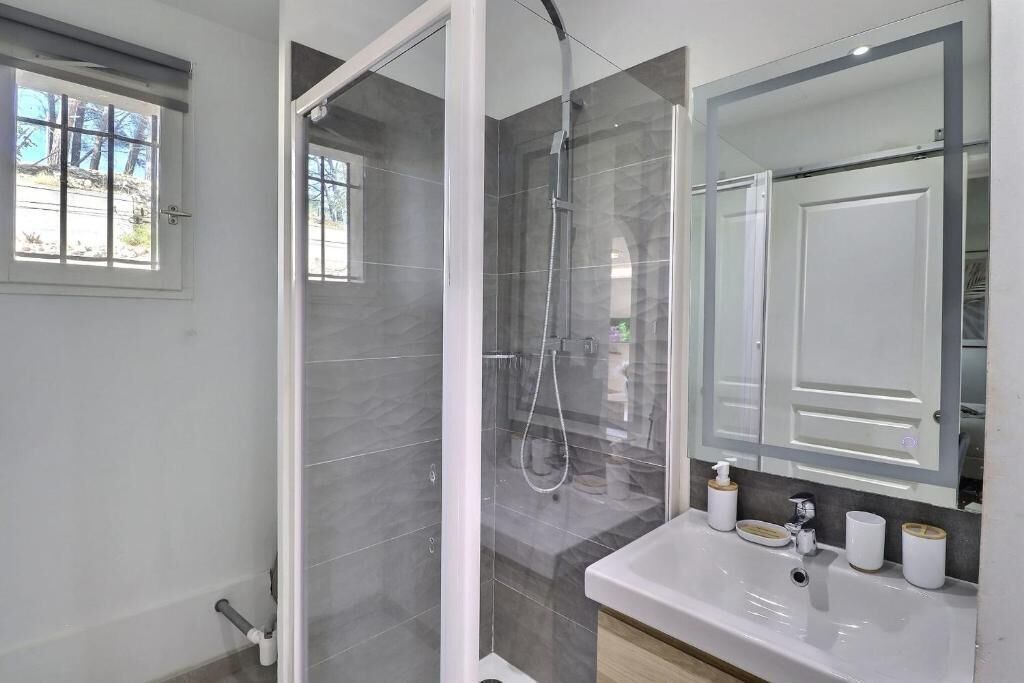 A modern bathroom with a shower, a sink, and a mirror.