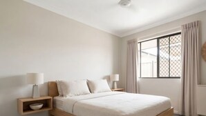 A modern bedroom with a bed, bedside tables, and a window with curtains. - Zen Courtyard Garden - Patio - Garage (Darwin)