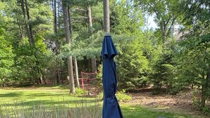 Ein Patio-Tisch mit vier Stühlen und einem blauen Sonnenschirm.