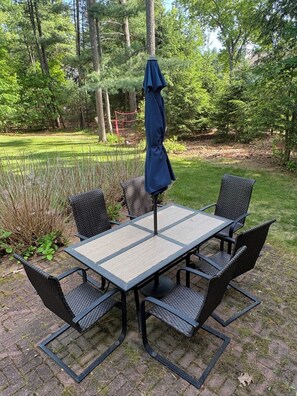 Ein Patio-Tisch mit vier Stühlen und einem blauen Sonnenschirm.