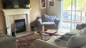 Ein Wohnzimmer mit Kamin, Fernseher, Sofa und Couchtisch.
