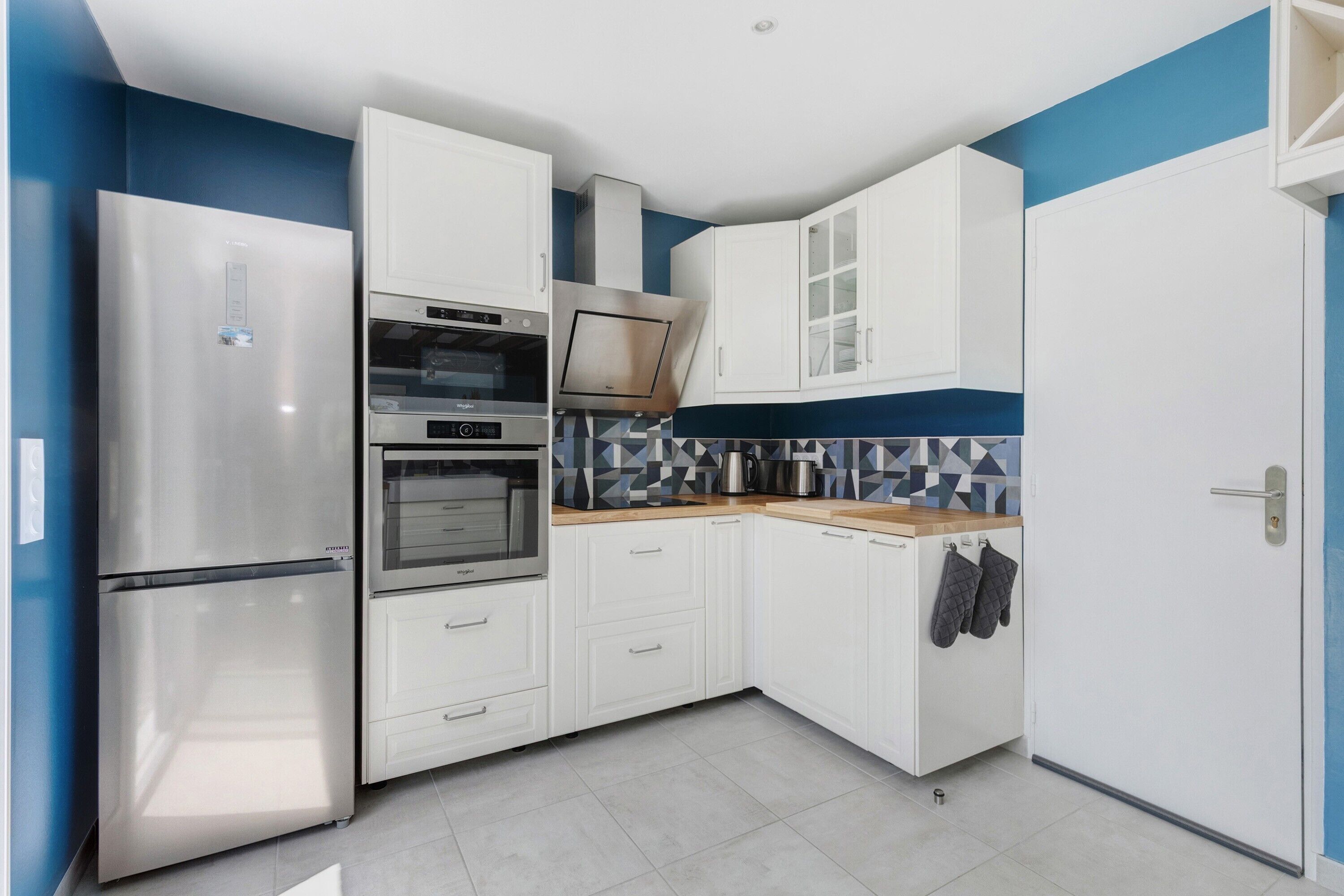 A compact kitchen with white cabinets, a stainless steel refrigerator, an oven, and a microwave.