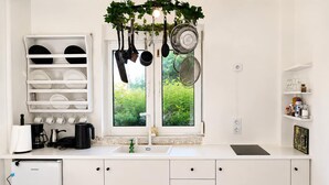 Una cucina moderna con mobili bianchi, forno integrato, macchina per caffè e una finestra vista verde.
