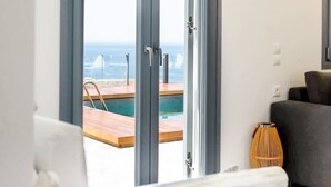 Una habitación con vista a una piscina y al mar, una puerta corrediza de vidrio, un sofá y una silla.