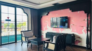 Una habitación con un ventanal grande, un televisor de pantalla plana en la pared, un sofá, una mesita de centro y un armario.