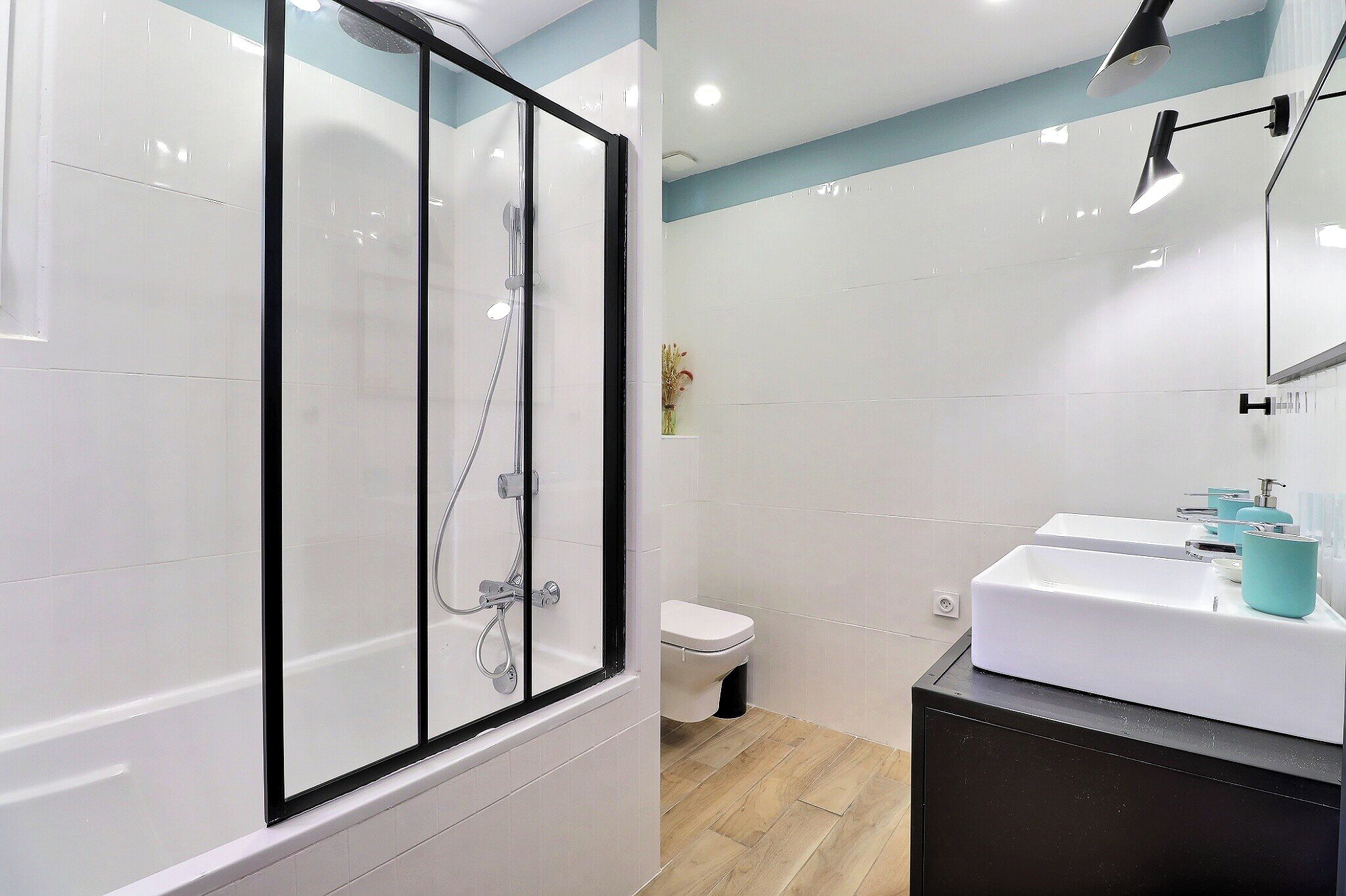 Une salle de bain moderne avec une douche à parois de verre, un lavabo blanc et des toilettes.