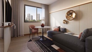 Ein modernes Hotelzimmer mit einer Couch, einem kleinen runden Tisch, einem Fernseher und einem großen Fenster mit Blick auf die Stadt.