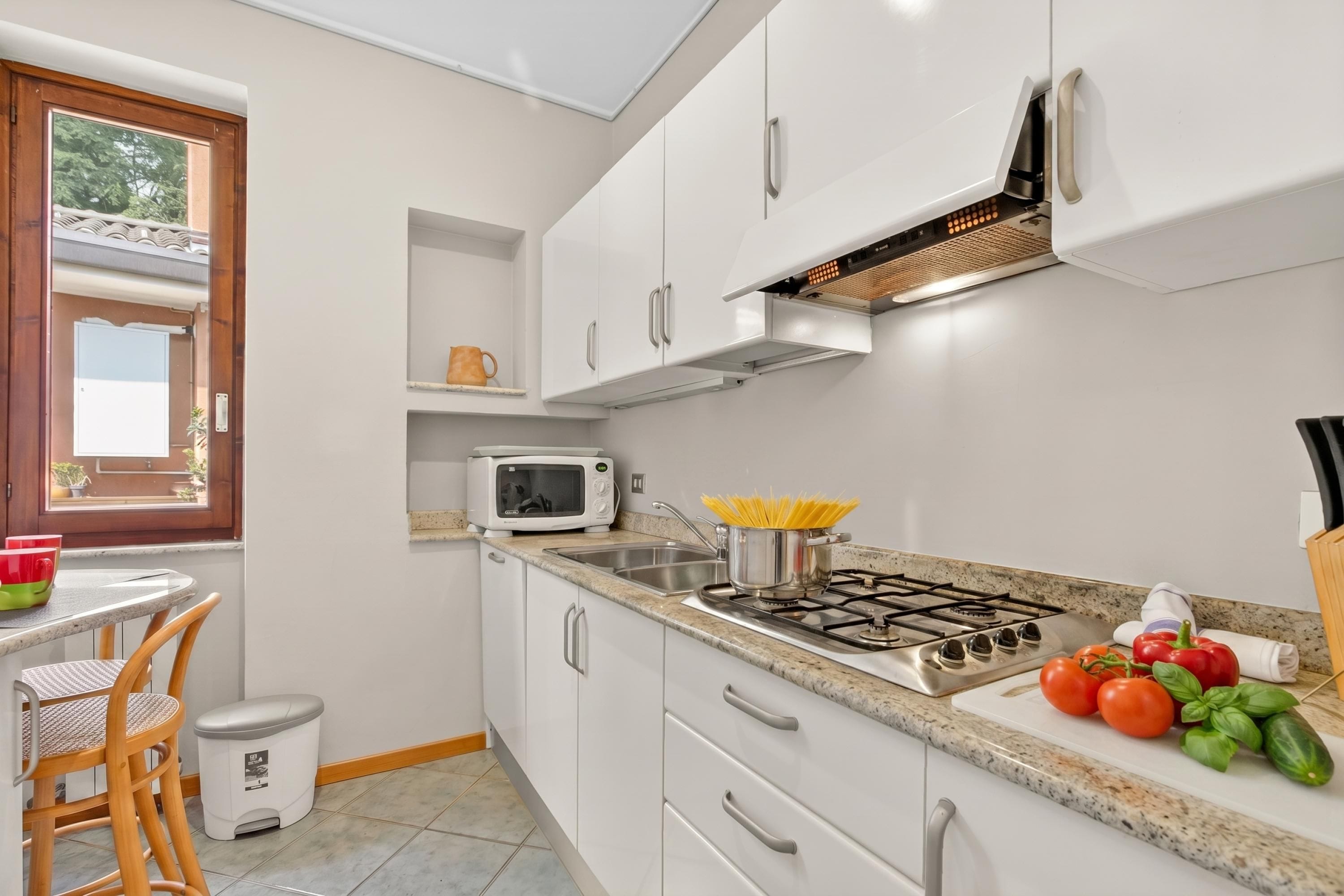 A modern kitchen with white cabinets, a microwave, a gas stove, and a window.