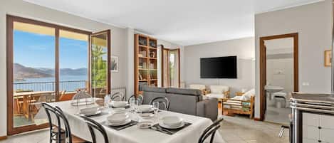 A dining area with a table set for four, a sofa, a TV, and a view of the mountains.