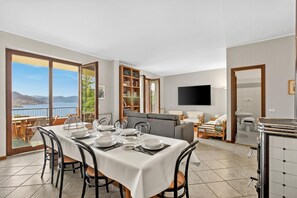 Un coin repas avec une table dressée pour quatre personnes, un canapé, un téléviseur et une vue sur les montagnes.