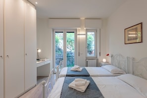 Ein Schlafzimmer mit zwei Betten, einem Schreibtisch und Blick ins Grüne.