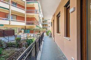 Un immeuble à plusieurs étages, doté de balcons, d’un étroit couloir et d’un mur en briques.