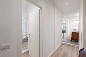 Ein Flur mit einer weißen Tür, einem Holzschrank und einer Treppe, die in einen anderen Raum führt.