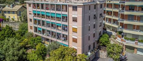 Un edificio de varios pisos con balcones, un estacionamiento y zonas verdes circundantes.