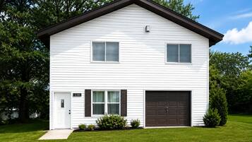 Une maison à deux étages avec un garage, une porte d’entrée et une boîte aux lettres.