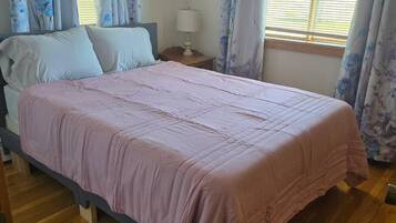 Une chambre à coucher avec un lit, un plancher en bois, des rideaux et une fenêtre.
