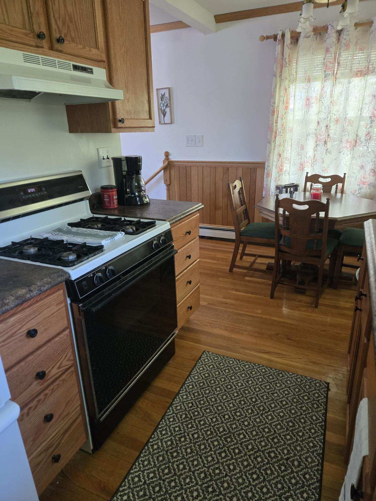 Une cuisine dotée de meubles en bois, d’une cuisinière, d’une machine à café et d’un coin repas avec une table et des chaises.