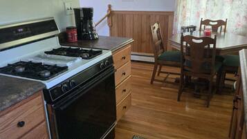 Une cuisine dotée de meubles en bois, d’une cuisinière, d’une machine à café et d’un coin repas avec une table et des chaises.