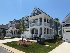 A two-story residential building with a balcony, a garage, and a well-maintained lawn. - Newly constructed home in The Peninsula - 23708 Brickwalk ~ (Millsboro)