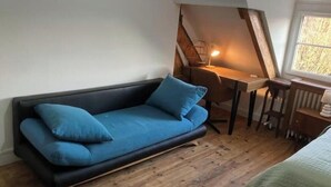 A loft-style room with a sofa, a desk, and a chair. - Cosy apartment with 2 fully-equipped studios in Saint-Pierre-des-Corps, near train station (Saint-Pierre-des-Corps)