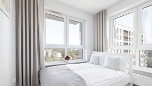 A modern bedroom with a bed, large windows, and a view of buildings. - Spacious Apartment with a Balcony | Parking (Lublin)